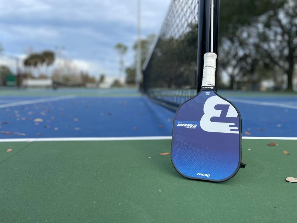 BOOMA pickleball paddle by a net on the court.