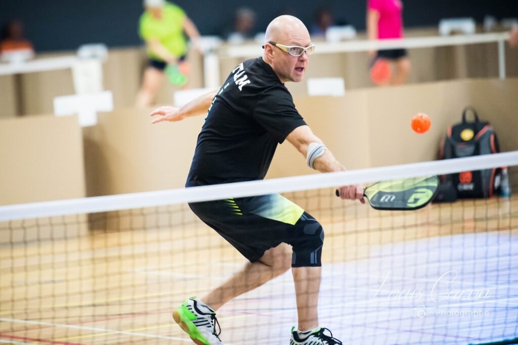 Image d'un joueur de pickleball qui frappe une balle de pickleball.